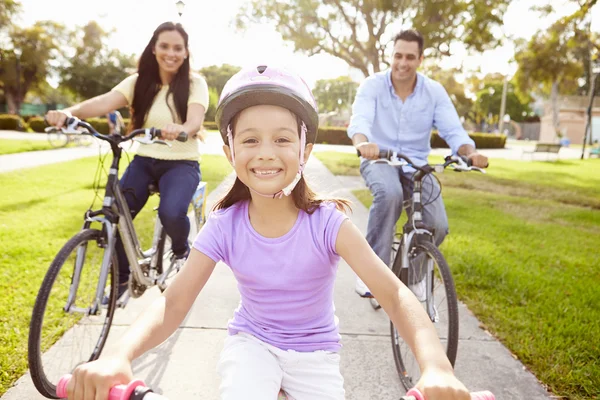 Родители с дочерьми катаются на велосипедах в парке — стоковое фото