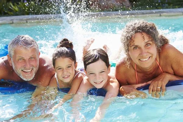 Mor-och farföräldrar med barnbarn i poolen — Stockfoto