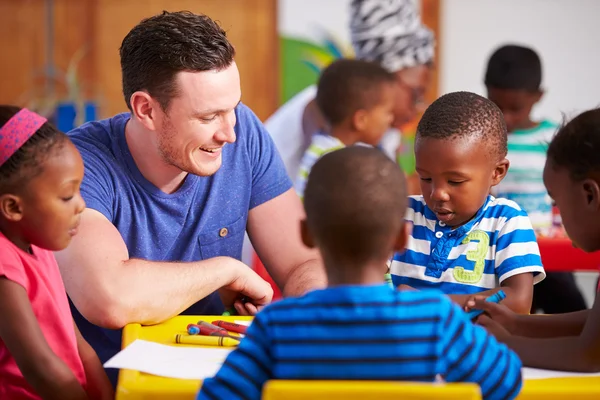 Insegnante volontario seduto con bambini in età prescolare — Foto Stock