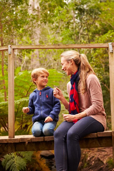 Mother and son sitting on a bridge — Stock Photo, Image