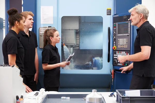 Aprendizes trabalhando com engenheiro em máquinas CNC — Fotografia de Stock