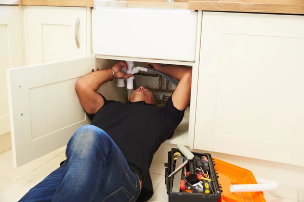 Um encanador que fixa uma pia de cozinha — Fotografia de Stock