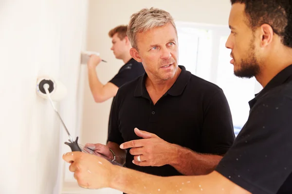 Decorador instruindo colega pintando uma sala — Fotografia de Stock