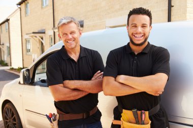 Young and a middle aged tradesmen by their van clipart