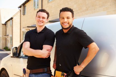 Two young tradesmen by their van clipart