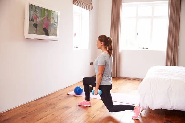 Kvinna som arbetar ut till Fitness Dvd på Tv — Stockfoto