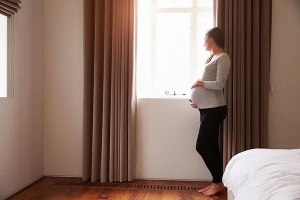 妊娠中の女性が窓のそばに立って — ストック写真