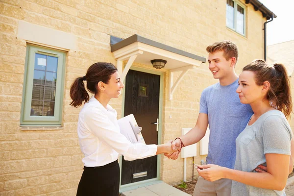 Agente imobiliário apertando as mãos com os proprietários — Fotografia de Stock