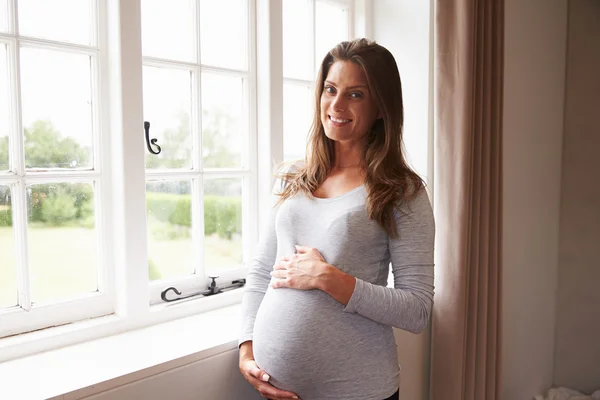 Gravid kvinna som står vid fönstret — Stockfoto