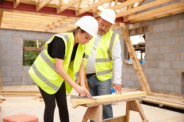 Timmerman met leerling die op bouwplaats werkt — Stockfoto