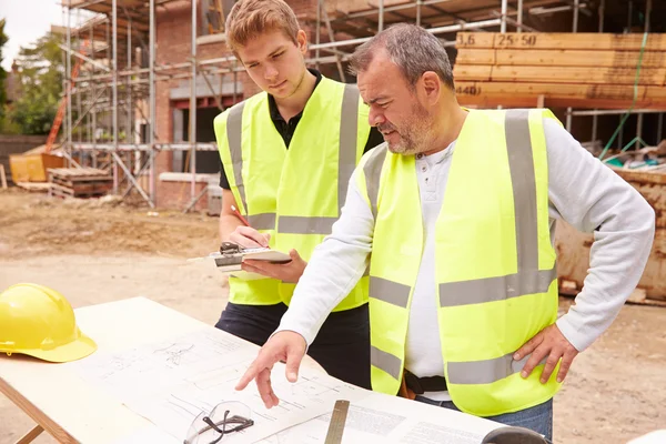 Bauarbeiter bespricht Arbeit mit Lehrling — Stockfoto