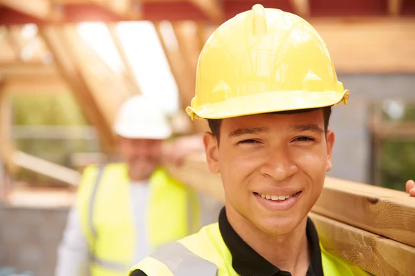 Bauarbeiter und Lehrling tragen Holz auf Baustelle — Stockfoto