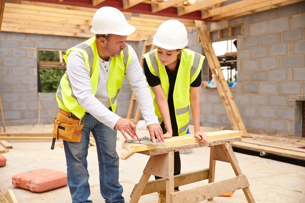 Carpinteiro com aprendiz trabalhando no canteiro de obras — Fotografia de Stock