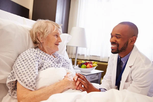 Доктор разговаривает со старшим пациентом в постели — стоковое фото