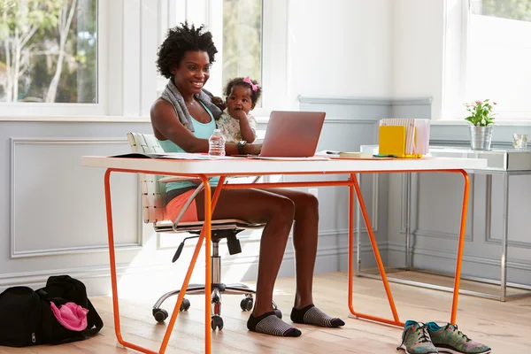 Mujer sosteniendo niño usando computadora — Foto de Stock