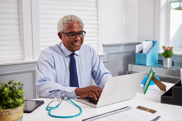 Starszy lekarz korzysta z laptopa w biurze — Zdjęcie stockowe