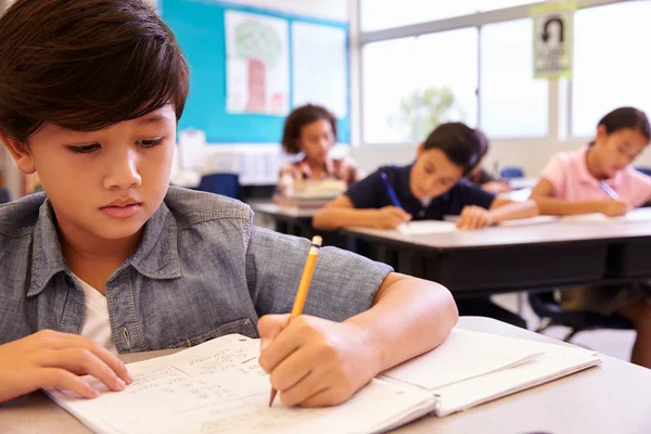 Skolpojke som arbetar i grundskolan klass — Stockfoto