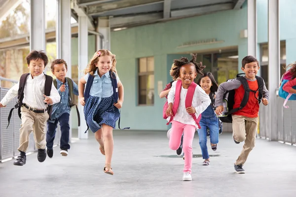 Grupa dzieci biegają w szkolnym korytarzu — Zdjęcie stockowe