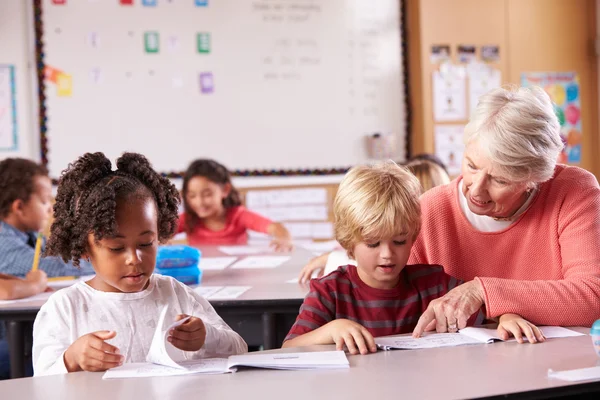 Starszy nauczyciel pomaga uczniom w klasie — Zdjęcie stockowe