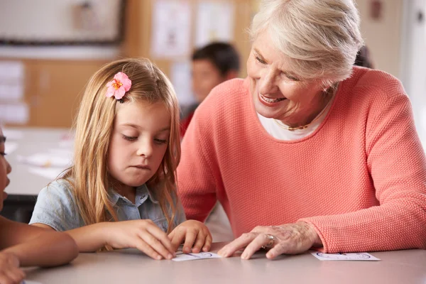 Senior teacher helping schoolgirl — Stock Photo, Image