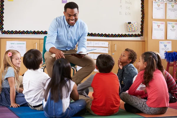 Niños sentados alrededor del profesor en un aula — Foto de Stock