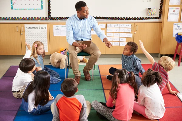 Дети сидят вокруг учителя на уроке — стоковое фото