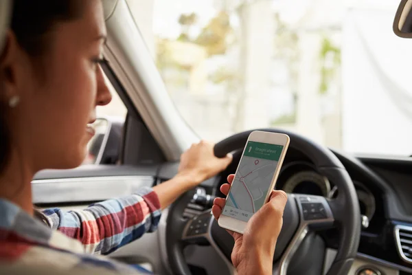 Женщина-водитель смотрит на Maps App — стоковое фото