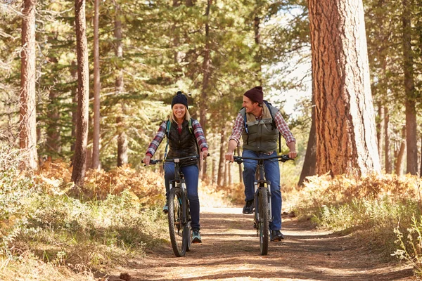 Couple mountain biking through forest — Stock Photo, Image