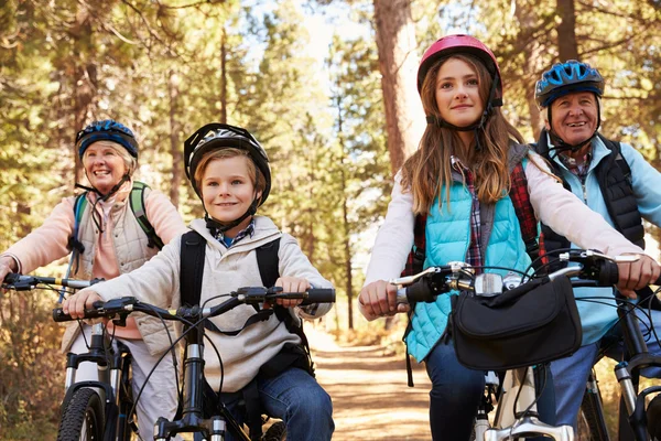 Grandparents and grandkids cycling on forest trail