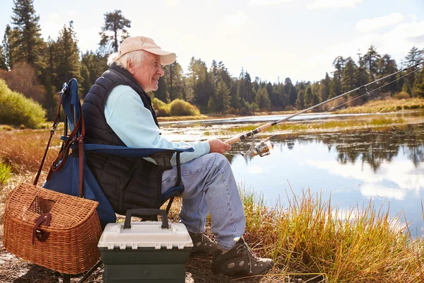 Uomo anziano pesca in un lago — Foto Stock