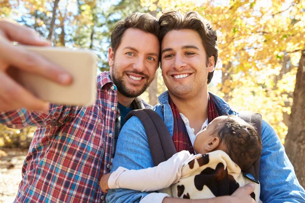 Casal masculino com bebê tomando selfie — Fotografia de Stock