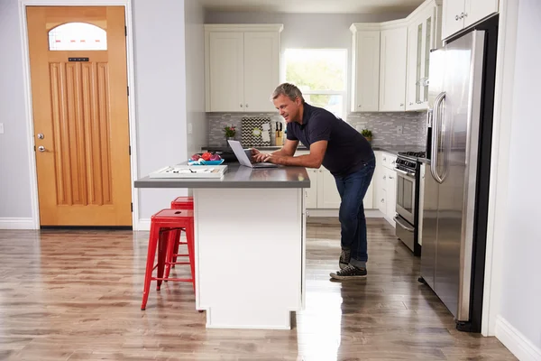 Hombre usando el ordenador portátil en la cocina — Foto de Stock