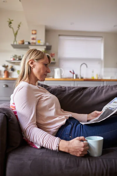 Frau liest Zeitung in moderner Wohnung — Stockfoto