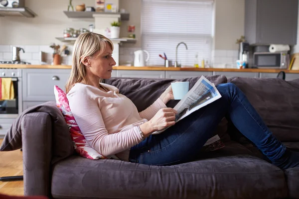 Frau liest Zeitung in moderner Wohnung — Stockfoto