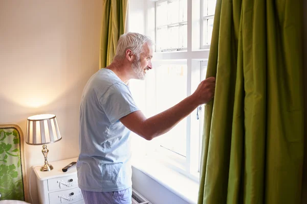 Hombre abriendo las cortinas en la habitación del hotel — Foto de Stock