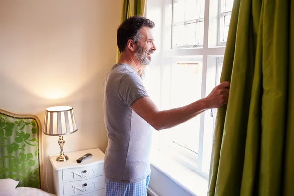 Homme ouvrant rideaux dans la chambre d'hôtel — Photo