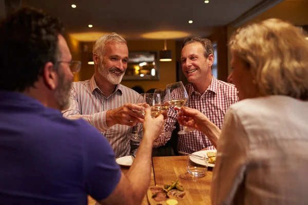 Vier vrienden maken een toast in een restaurant — Stockfoto