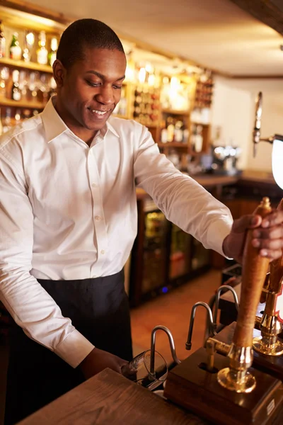 Man working behind a bar preparing drinks — Stock Photo, Image