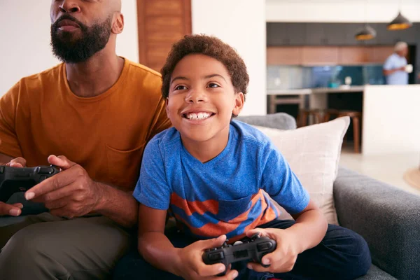 非裔美国人的父亲和儿子一起坐在沙发上玩电子游戏 — 图库照片