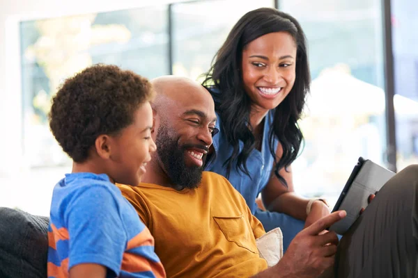非洲裔美国人家庭 儿子坐在沙发上在家使用数码记事板 — 图库照片