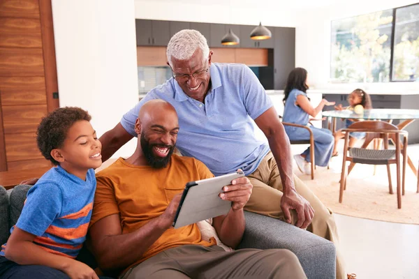 多代非洲裔美国男性家庭坐在沙发上使用数码记事板 — 图库照片