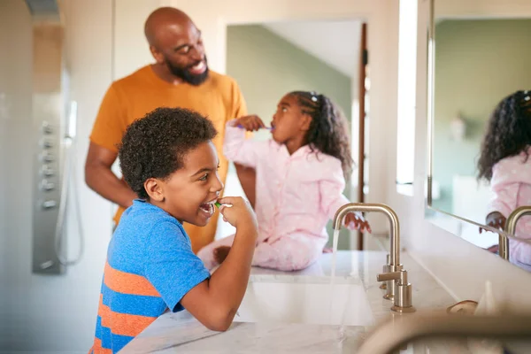 Padre Ayudando Los Niños Cepillarse Los Dientes Baño Casa —  Fotos de Stock