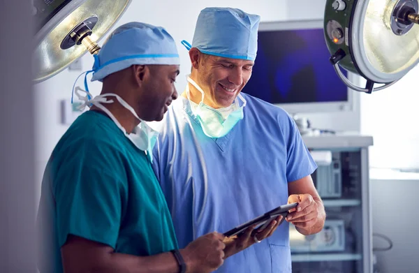 Αρσενικοί Χειρουργοί Φορώντας Γρατζουνιές Κοιτάζοντας Ψηφιακή Ταμπλέτα Στο Χειρουργείο Νοσοκομείο — Φωτογραφία Αρχείου