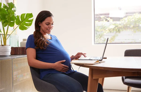 自宅のテーブルでノートパソコンを使う妊婦 — ストック写真