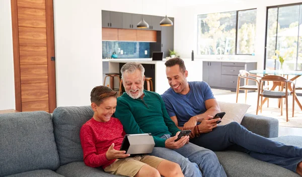 Familia Hispana Masculina Varias Generaciones Sentada Sofá Casa Usando Teléfonos —  Fotos de Stock