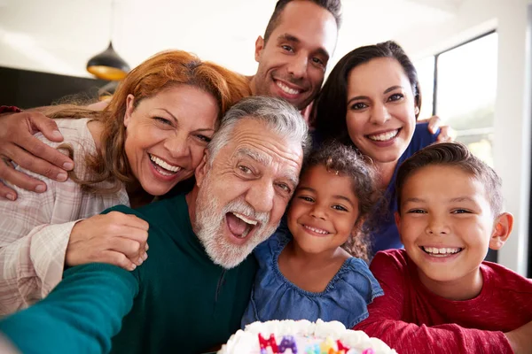 孫の誕生日を自宅で祝うためにセルフィーを取る世代のヒスパニック系の家族 — ストック写真
