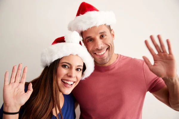 Retrato Casal Hispânico Vestindo Chapéus Papai Noel Celebrando Natal Acenando Fotografia De Stock