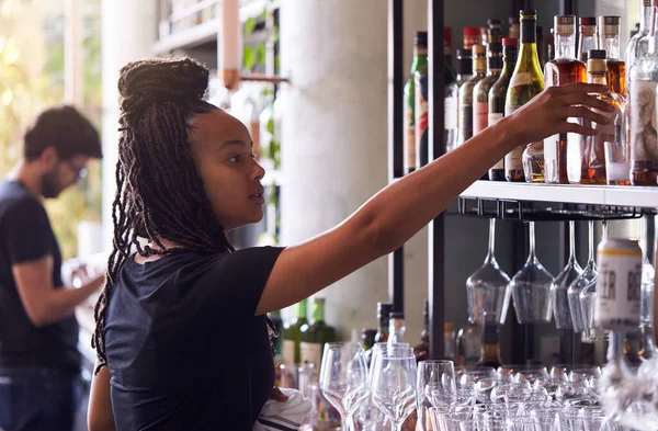 Vrouwelijke Barman Regelen Flessen Alcohol Achter Bar — Stockfoto
