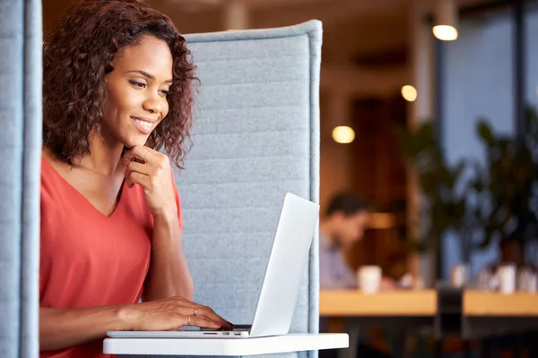 Businesswoman At Desk In Cubicle In Modern Office Work Space Using Laptop