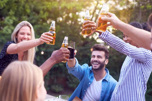 Friends Making Toast With Alcohol In Garden At Home Enjoying Summer Garden Party